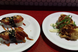 Unagi nigiri (left) and inari sushi stuffed with spicy tuna, crab and served with wasabi mayo, unagi sauce and sesame seeds